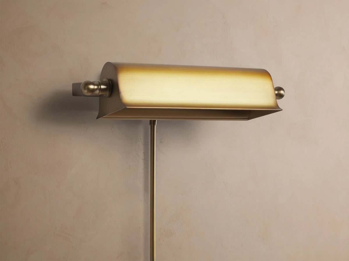 Tremont Picture Light Sconce with antiqued metallic gold finish mounted on a wall, casting a warm downward glow.