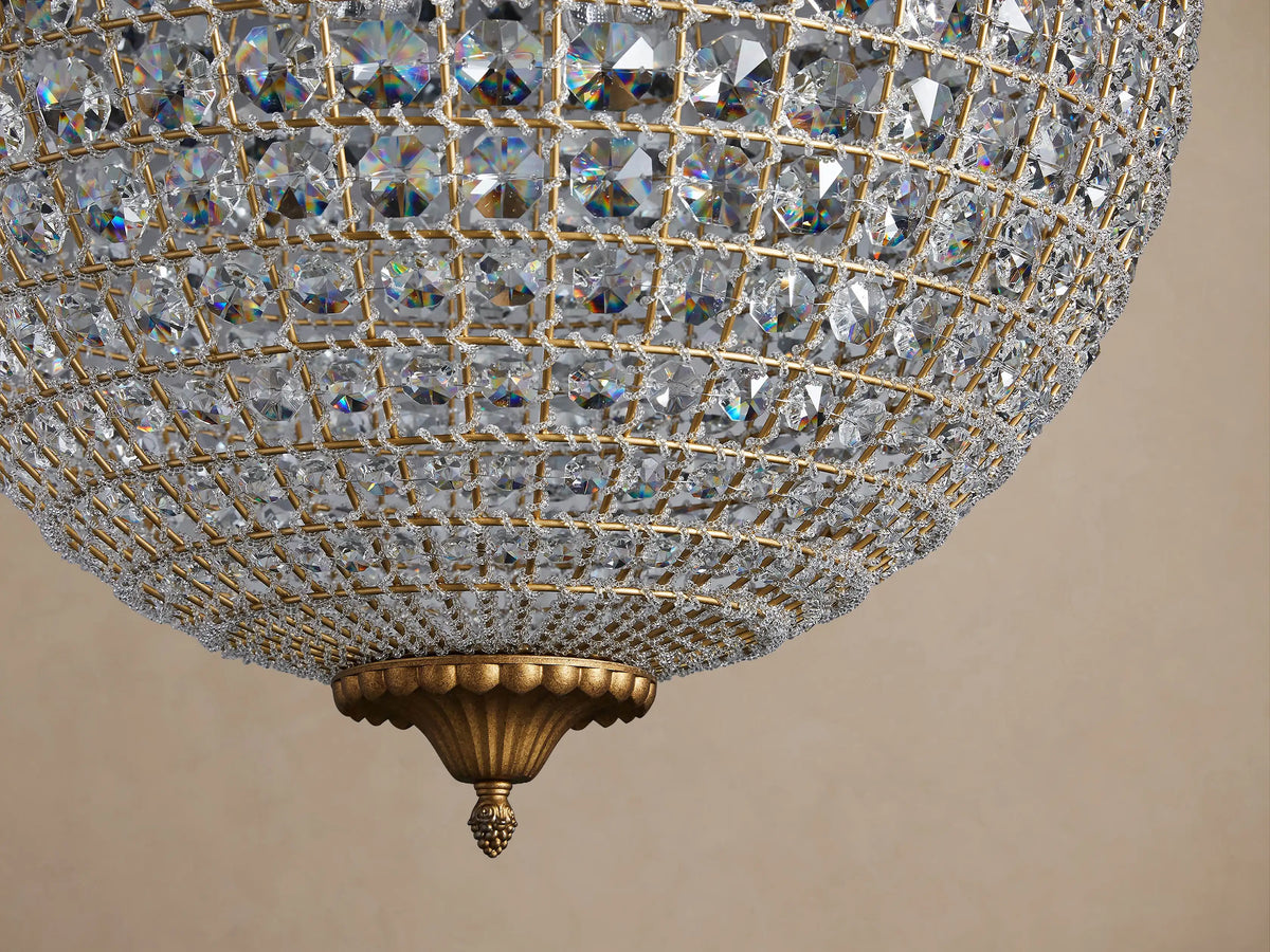 Poppy Chandelier. A sparkling spherical globe chandelier covered in faceted clear crystals with an antiqued brass frame.
