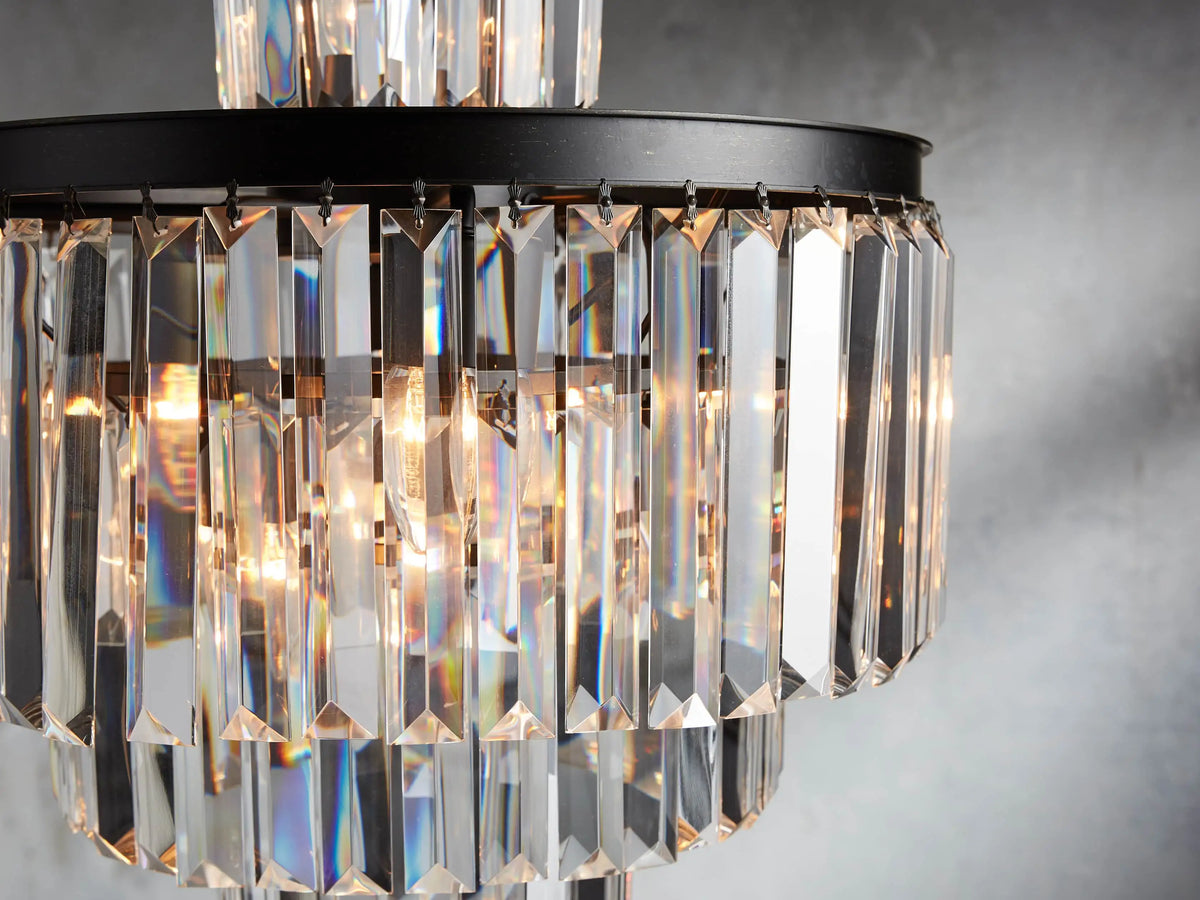 Leyland Chandelier with two tiers of clear K9 glass crystals on an oil-rubbed iron frame, emitting warm light against a grey wall.