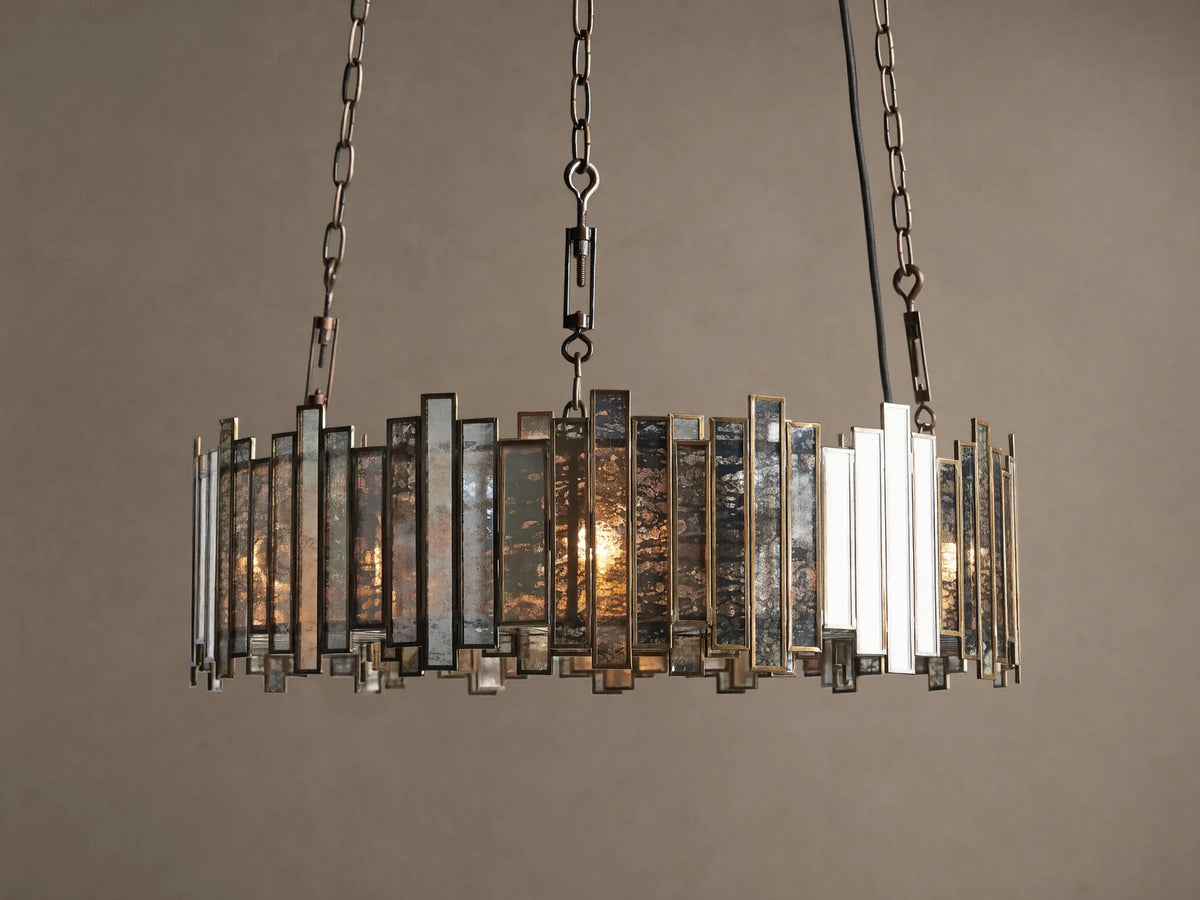 Laila Round Chandelier with an antique copper frame & irregular antiqued mirrored-glass panels, illuminated by warm lights.