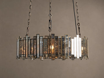 Laila Round Chandelier with an antique copper frame & irregular antiqued mirrored-glass panels, illuminated by warm lights.