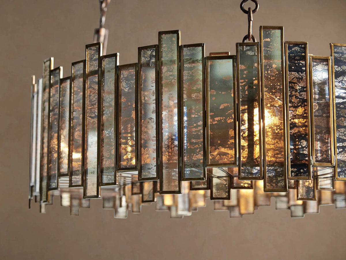 Laila Round Chandelier with an antique copper frame & irregular antiqued mirrored-glass panels, illuminated by warm lights.