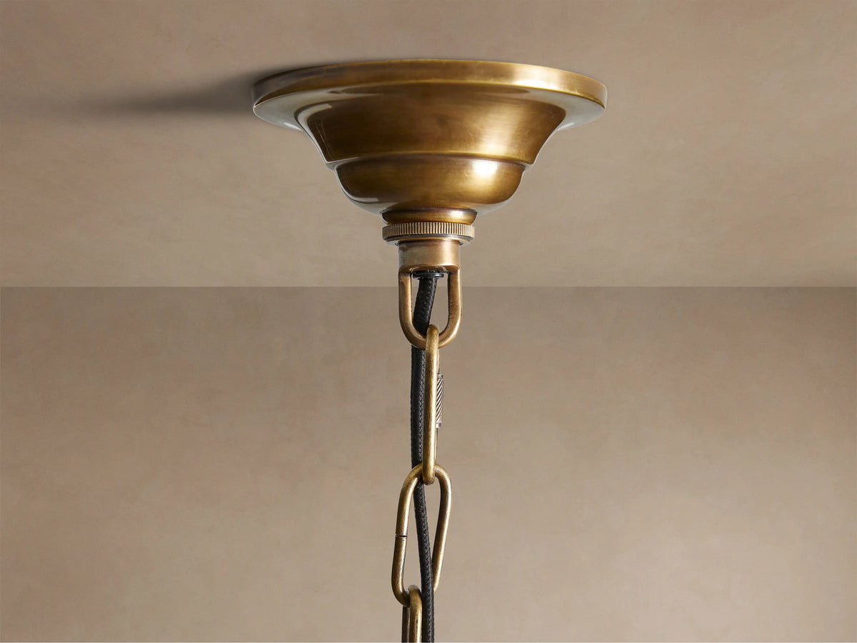 Close-up of Eliana Lantern Pendant: intricate gold brass geometric frame with clear glass panels, an E26 light bulb visible inside.