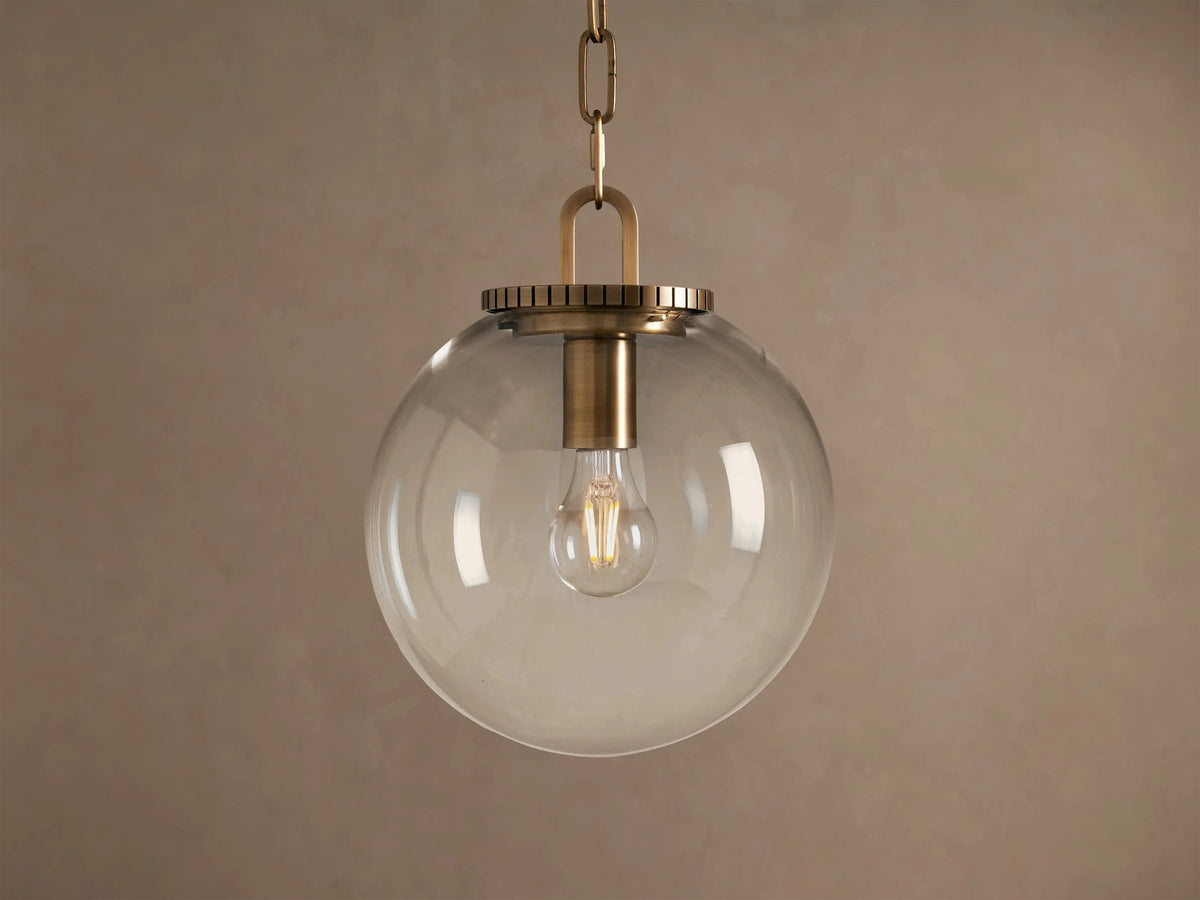 Wescott Globe Pendant: clear glass sphere with brass hardware and visible Edison bulb, hanging from a chain.