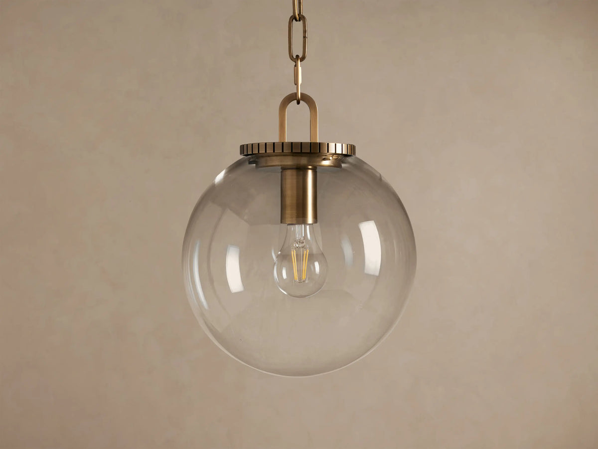Wescott Globe Pendant: clear glass sphere with brass hardware and visible Edison bulb, hanging from a chain.