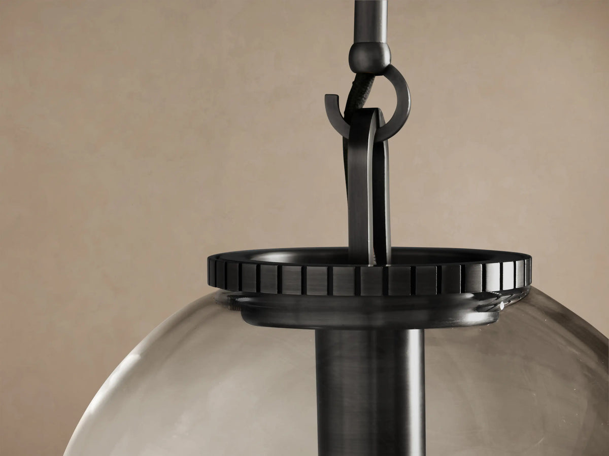 Wescott Globe Pendant: clear glass globe shade with an exposed Edison bulb, suspended by a dark steel rod on a plain wall.