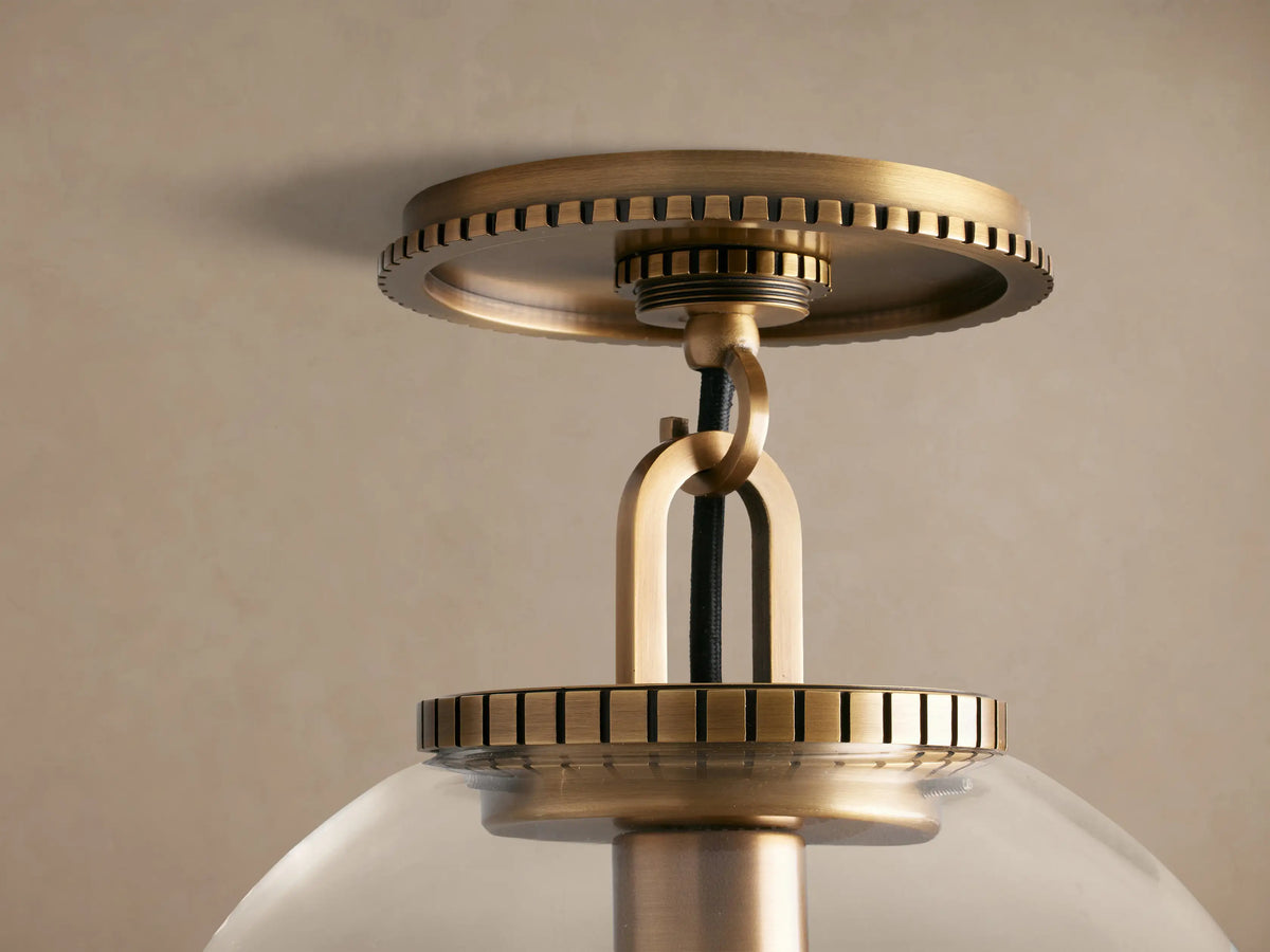 Wescott Globe Flush Mount with clear glass, exposed bulb, brass metal fixture, ridged canopy on a neutral ceiling.