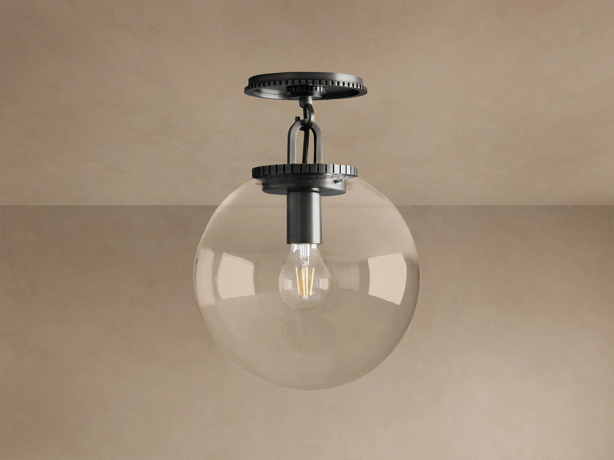 Wescott Globe Flush Mount light fixture with dark bronze hardware, clear glass globe, and exposed filament bulb, mounted on ceiling.