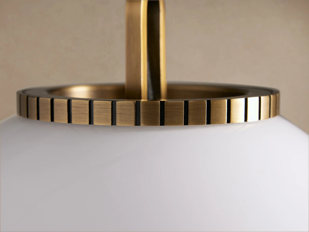 Wescott Globe Pendant with a large, white milky glass sphere and a brass chain with a ribbed cap, hanging.