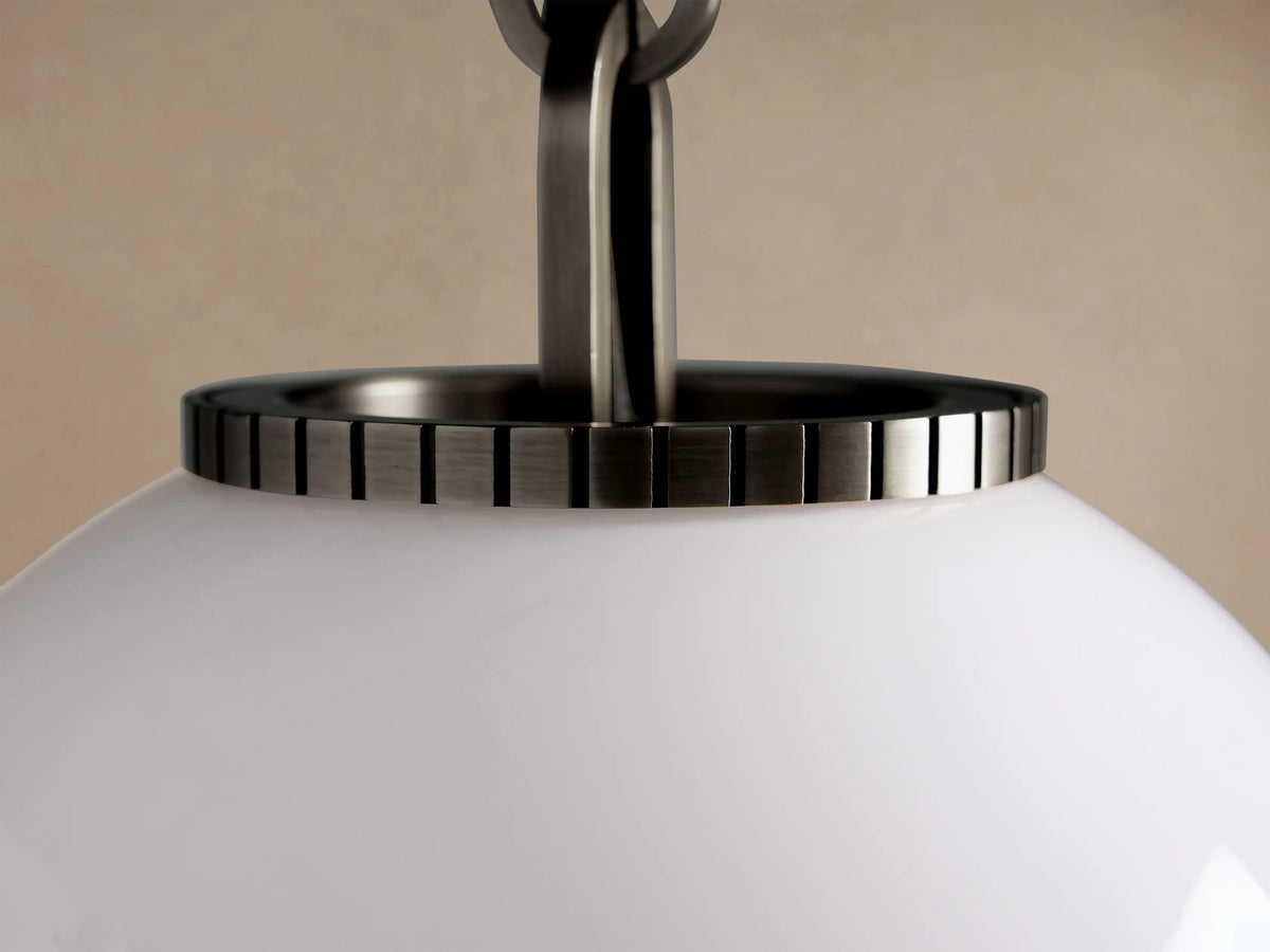 Wescott Globe Pendant with a white milk glass globe, dark metal cap, and chain hanging against a beige wall.