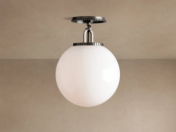 Wescott Globe Flush Mount with opaque white milk glass sphere and dark bronze hardware, against a light brown ceiling.