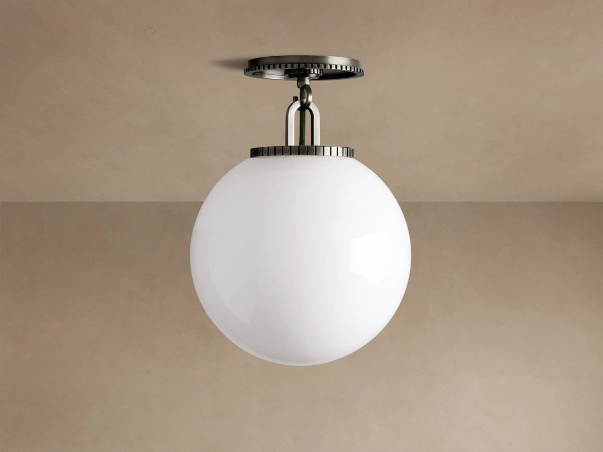 Wescott Globe Flush Mount with opaque white milk glass sphere and dark bronze hardware, against a light brown ceiling.