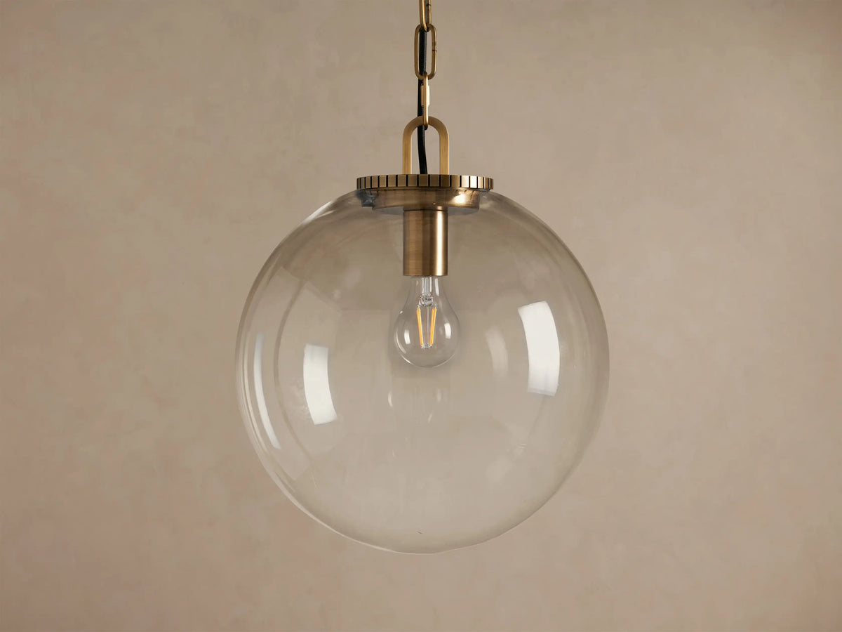 Wescott Globe Pendant with clear glass globe, brass finish chain, and visible bulb hanging against a neutral background.