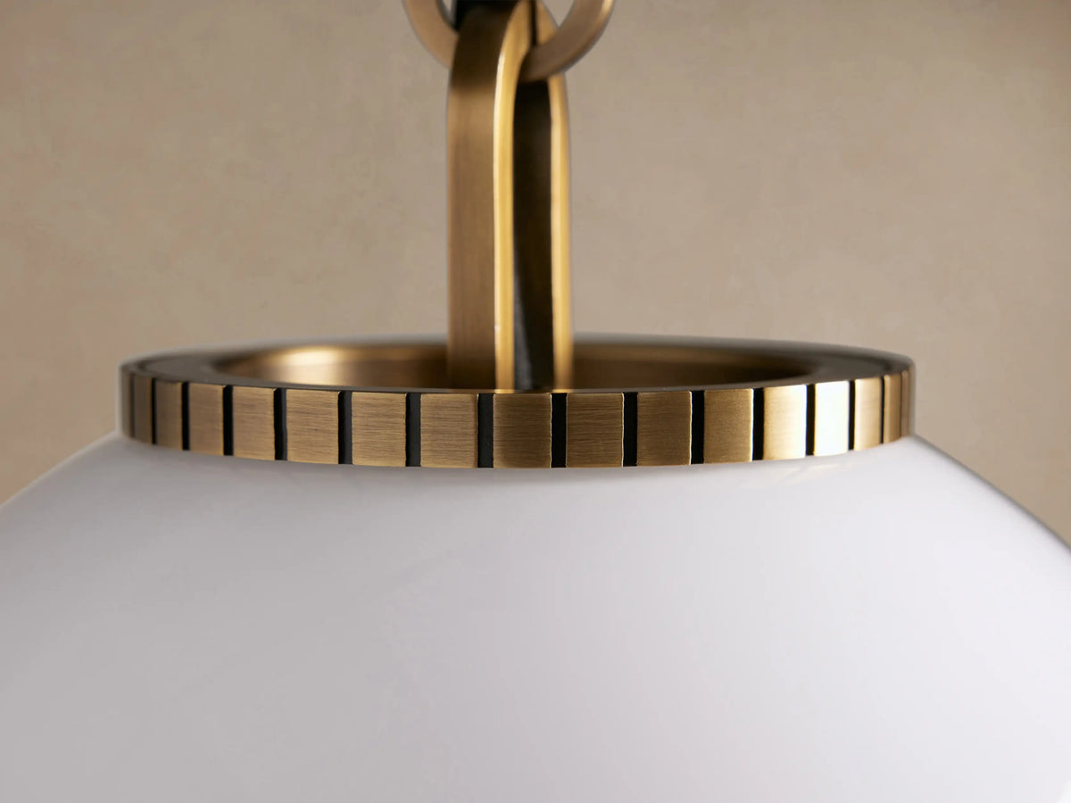 Wescott Globe Pendant: A large, white milk glass globe shade hangs from a brass rod and brass fitting against a beige wall.