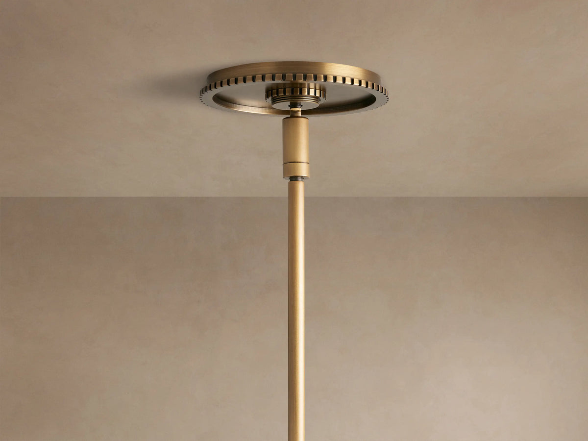 Close-up of Wescott Globe Pendant's brushed brass ring with black grooves, connecting to a white milk glass globe, brass rod.