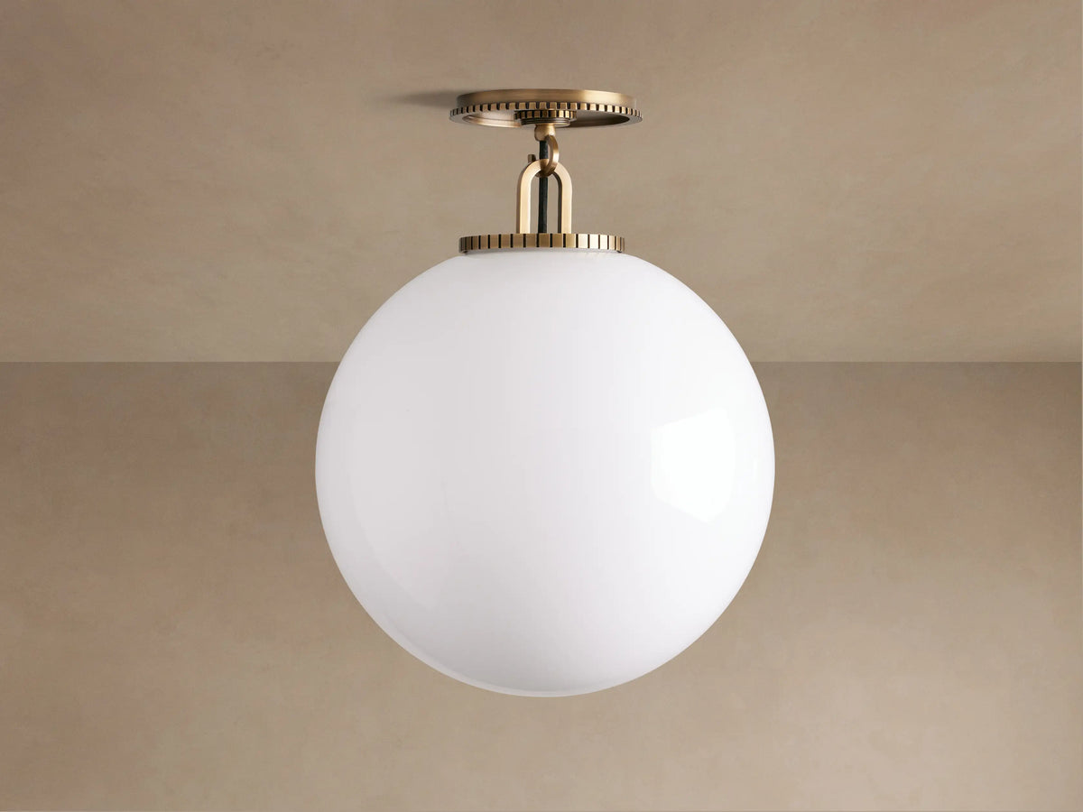 Wescott Globe Flush Mount: large white milk glass globe with ribbed brass hardware, mounted on a light tan ceiling.