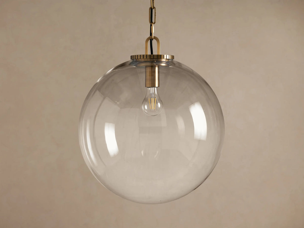 Wescott Globe Pendant with Chain, featuring a large, clear spherical glass shade, brass-finish hardware, and exposed bulb.