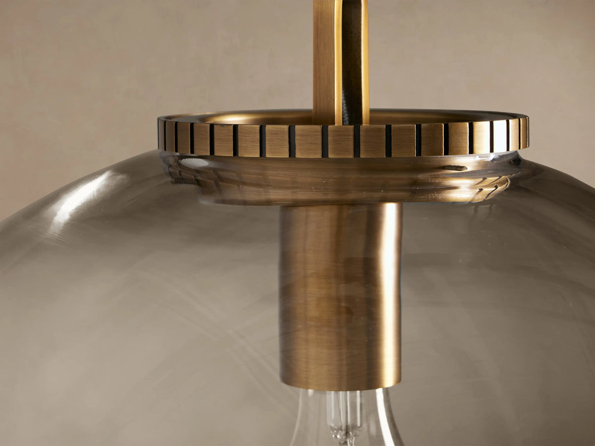 Wescott Globe Pendant: Clear glass sphere, brass finish hardware, and chain, hanging against a neutral wall.