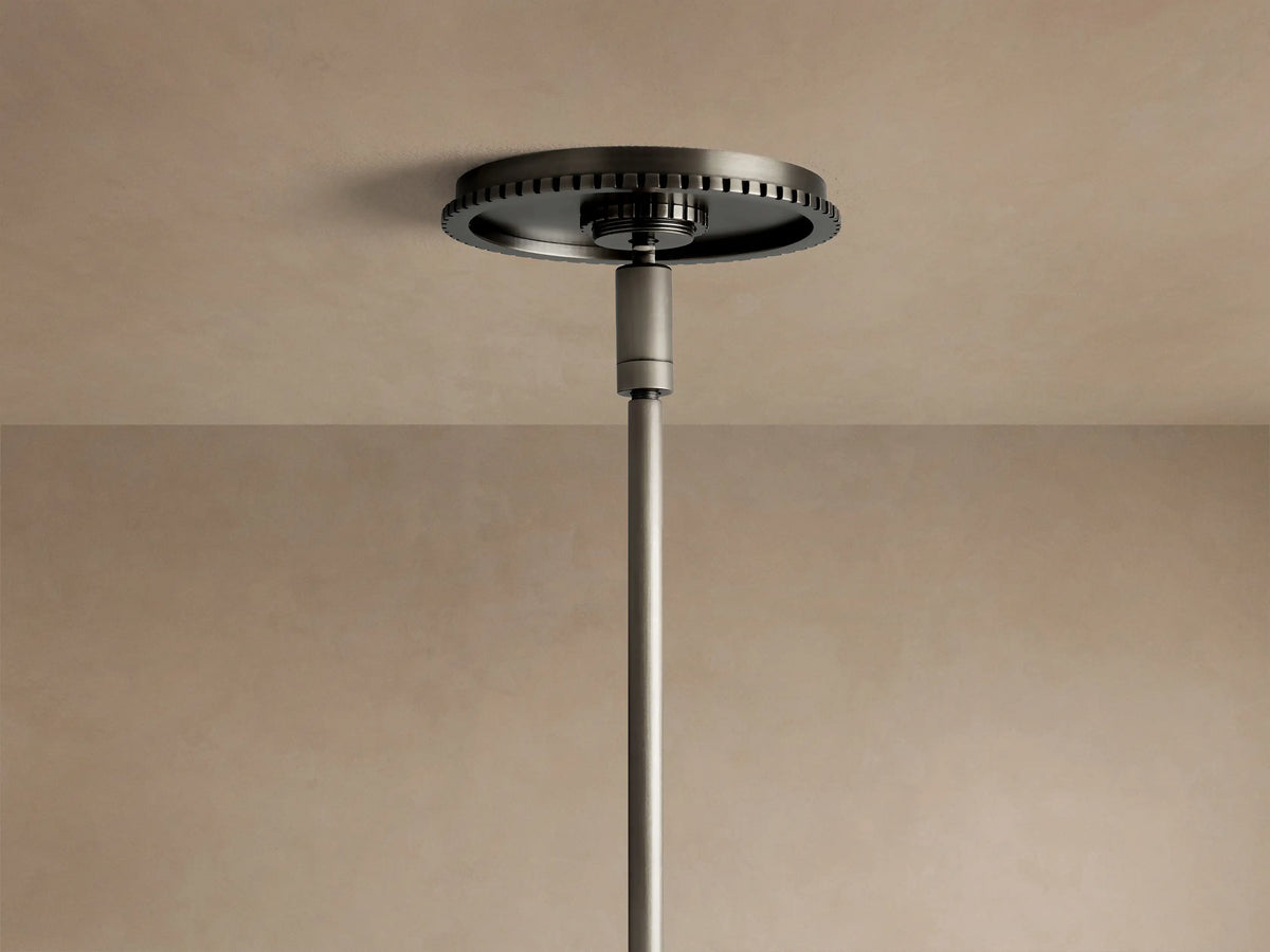 Wescott Globe Pendant close-up: dark bronze rod and ribbed cap connect to a clear glass globe, hanging against a wall.