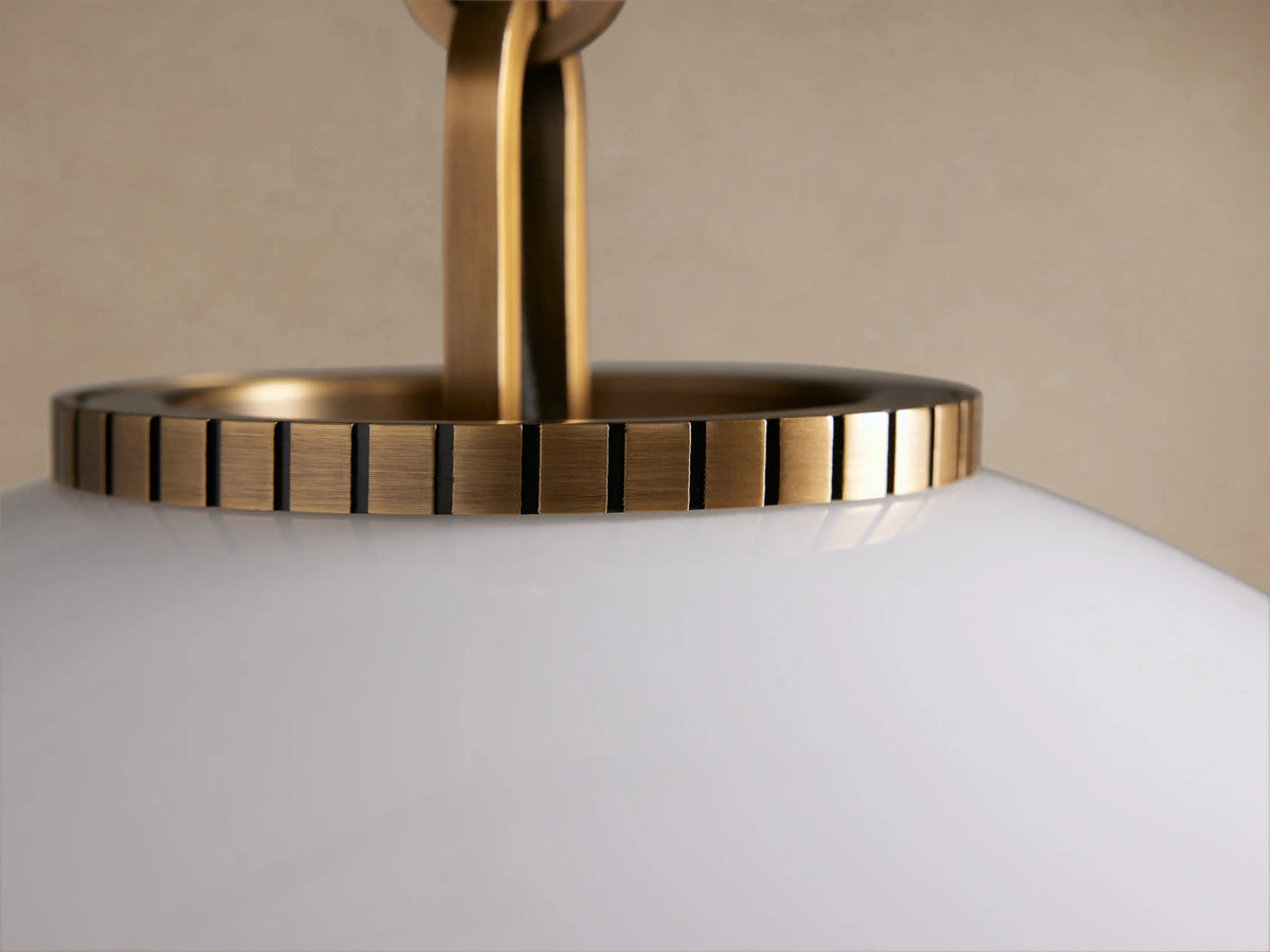 Wescott Globe Pendant with a large white milk glass globe hanging from a brass rod, detailed with ridged brass hardware.