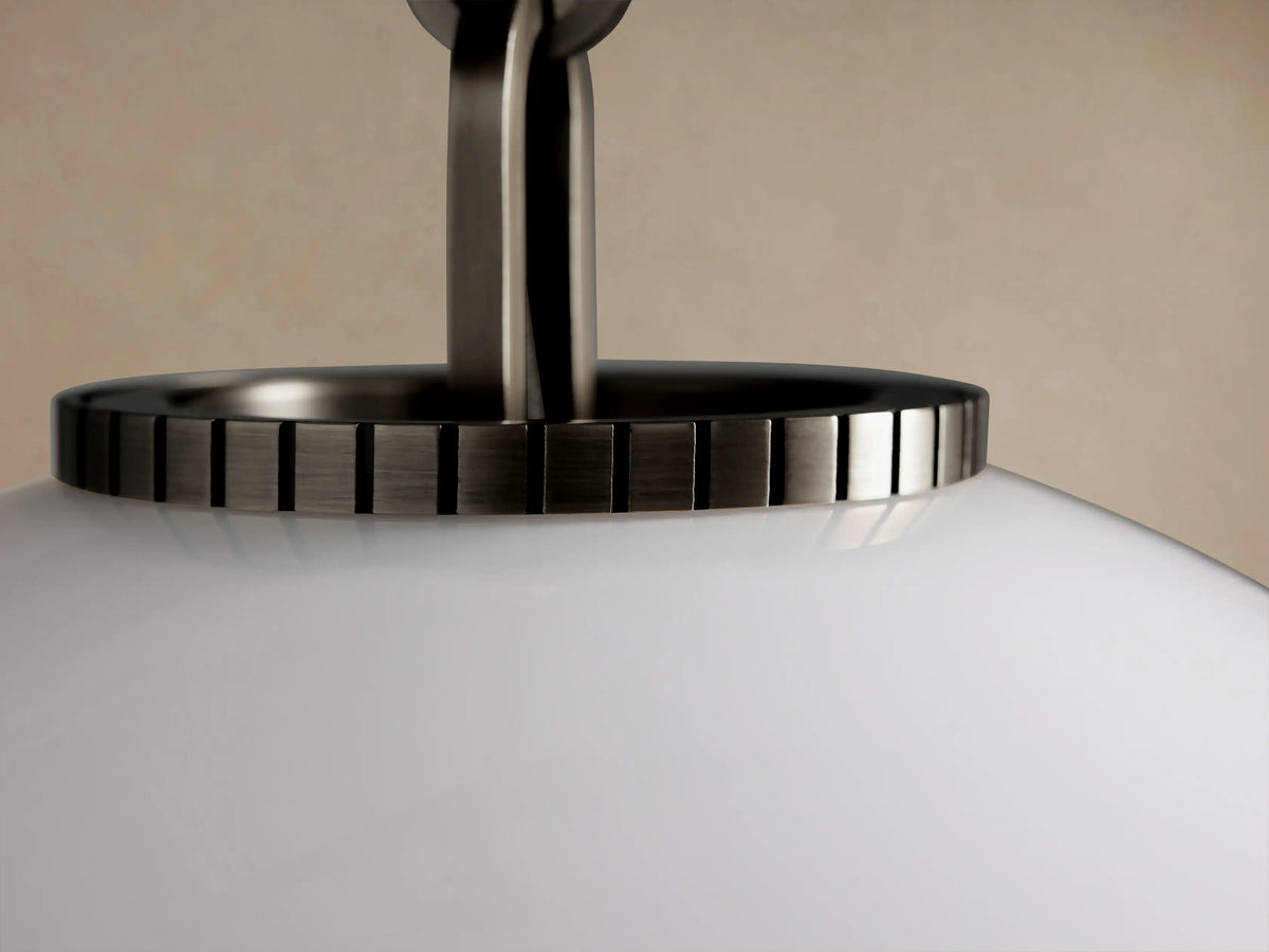 Wescott Globe Pendant: White milk glass globe light with a dark metallic rod, hanging vertically against a neutral wall.