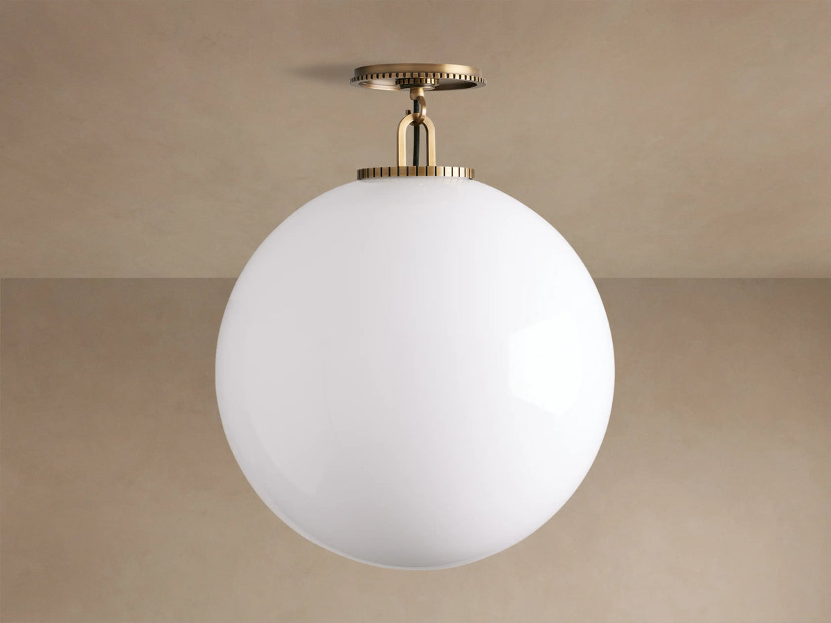 Wescott Globe Flush Mount, large white milk glass globe light with brass ribbed canopy, mounted on a ceiling.