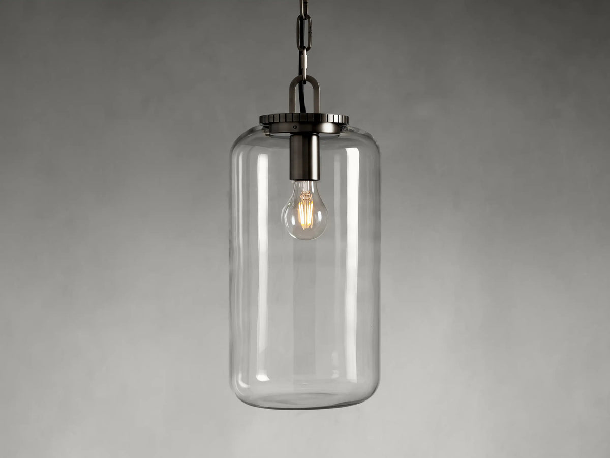 The Wescott Cylinder Pendant features a clear glass cylinder shade with visible filament bulb and brass or bronze fittings, suspended by a chain.