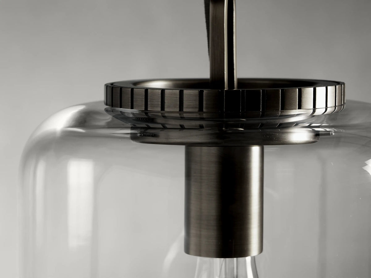 The Wescott Cylinder Pendant features a steel frame in a bronze finish, with a clear glass shade, close-up view showing detailed hardware.