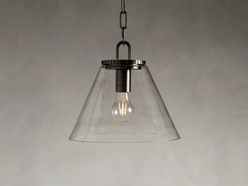 Clear conical glass pendant light with metal fittings in a bronze finish, hanging from a black fabric-wrapped cord and chain.