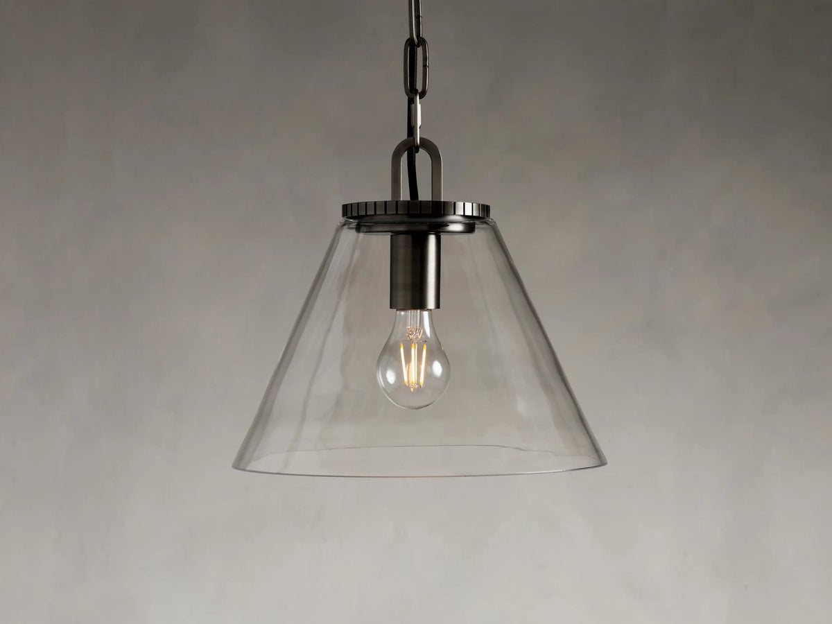 Cone-shaped pendant light with clear glass shade, suspended by a chain. Visible light bulb inside, with brass or bronze finish.