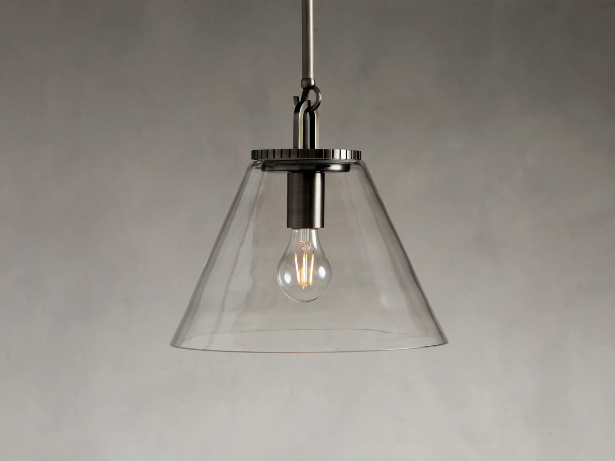 Clear glass cone pendant light with visible bulb, silver metal fixture, and adjustable silver rod on a neutral background.