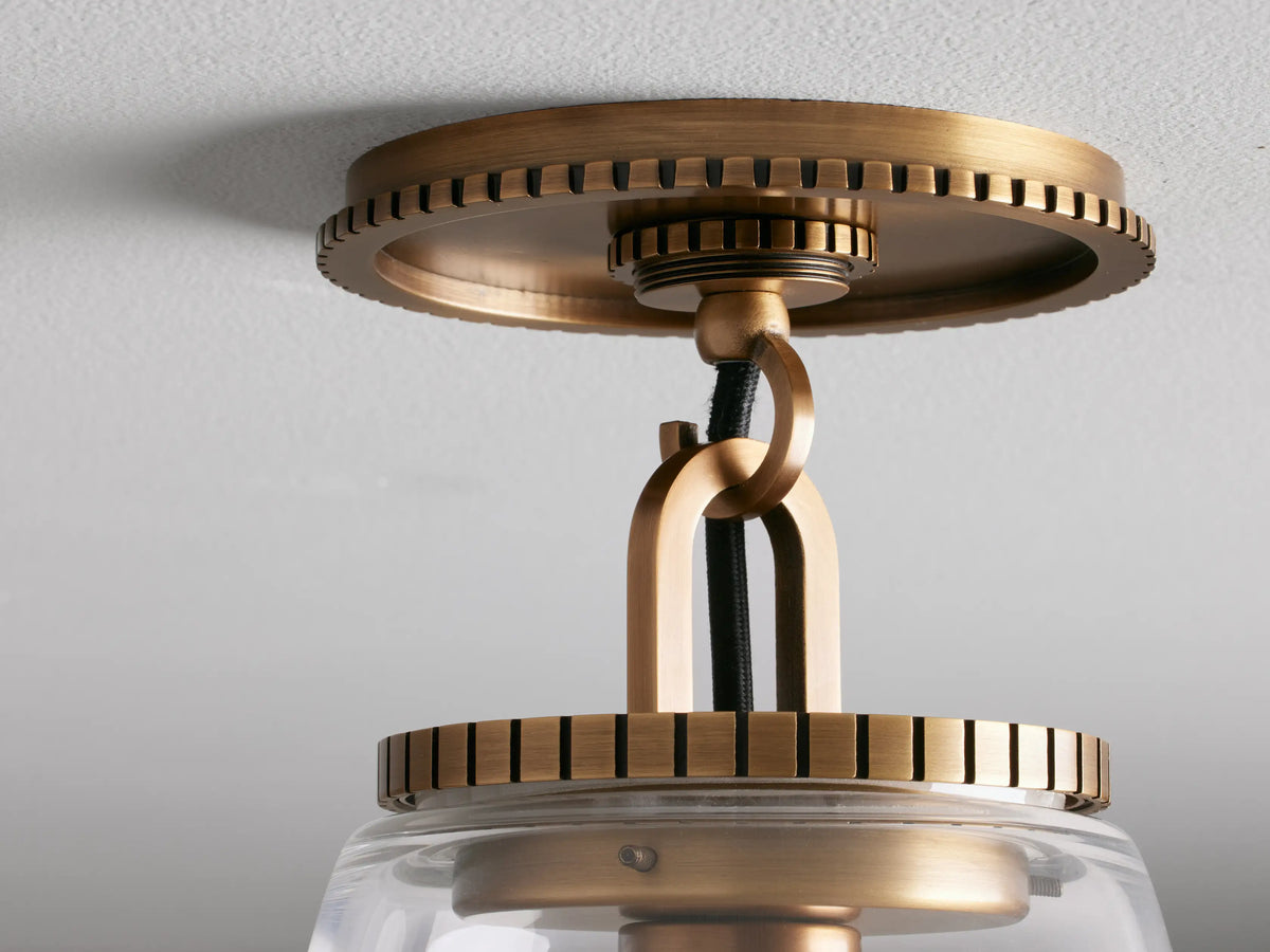 Wescott Cone Flush Mount in brass finish, featuring a clear glass shade and black fabric-wrapped cord, mounted on a ceiling.