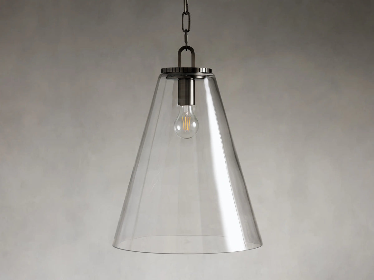 Pendant light with a clear glass cone shade, steel fixture in a brass or bronze finish, hanging from a black chain.