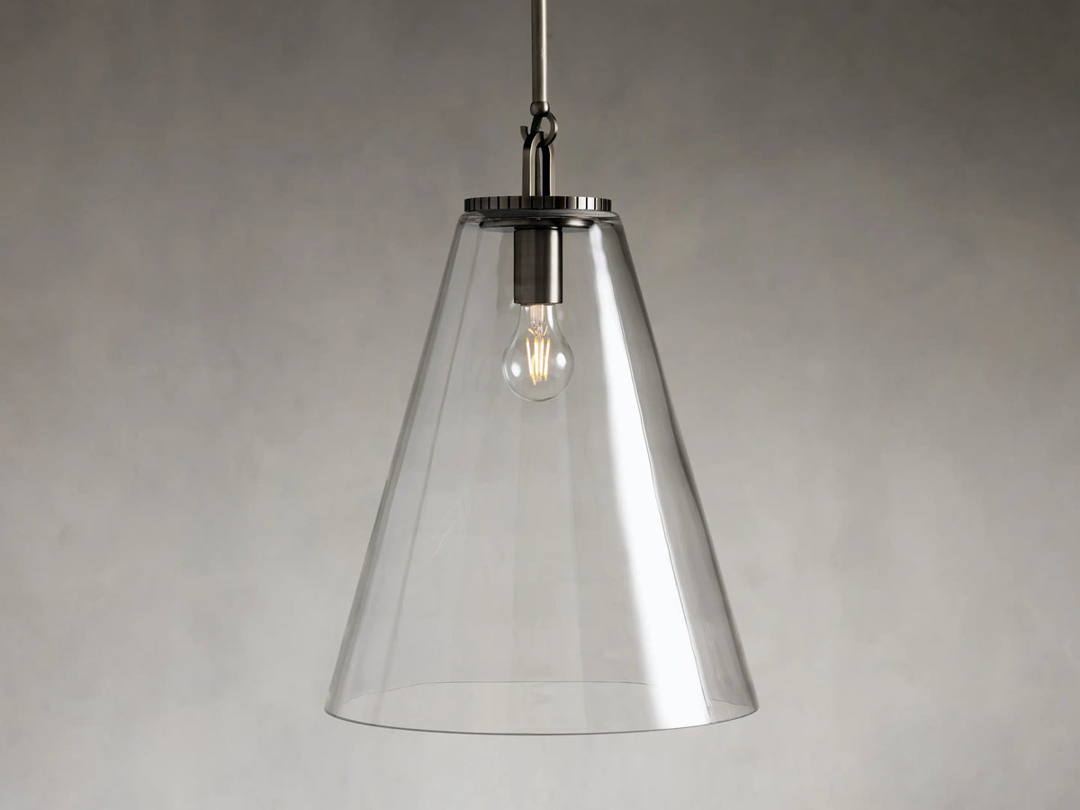 Clear glass cone pendant light with visible bulb and dark metal fixture, suspended from a rod against a gray background.