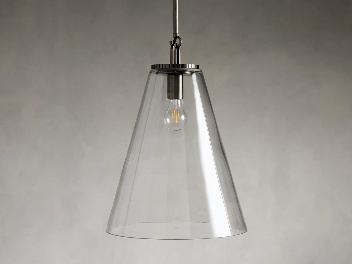 Clear glass cone pendant light with visible bulb and dark metal fixture, suspended from a rod against a gray background.