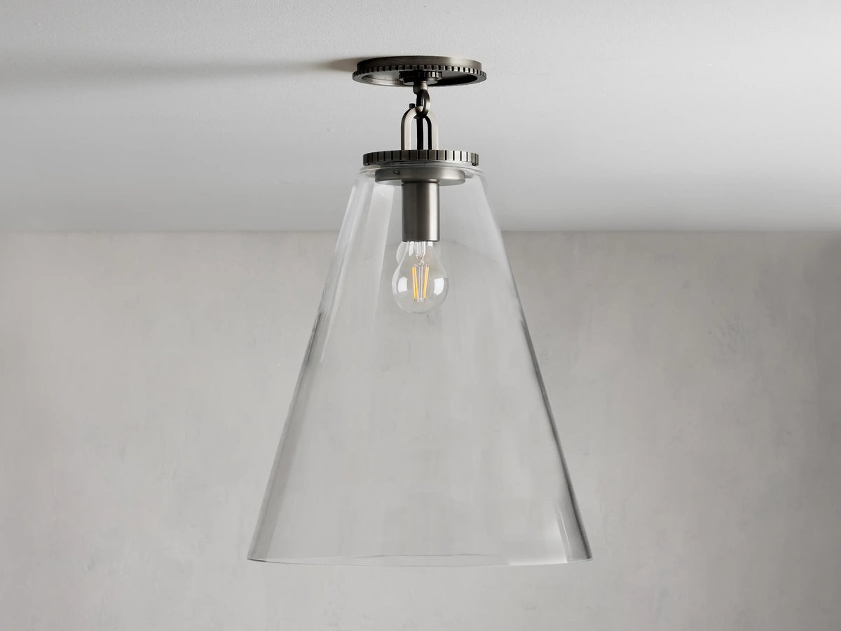 Clear glass cone shade flush mount light with visible bulb, metal fixture in dark finish, attached to white ceiling.