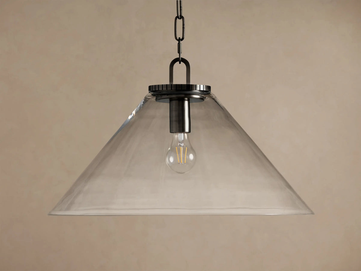 Wescott Cone Pendant: clear glass cone shade, dark bronze finish hardware, and exposed Edison bulb hanging against a tan wall.