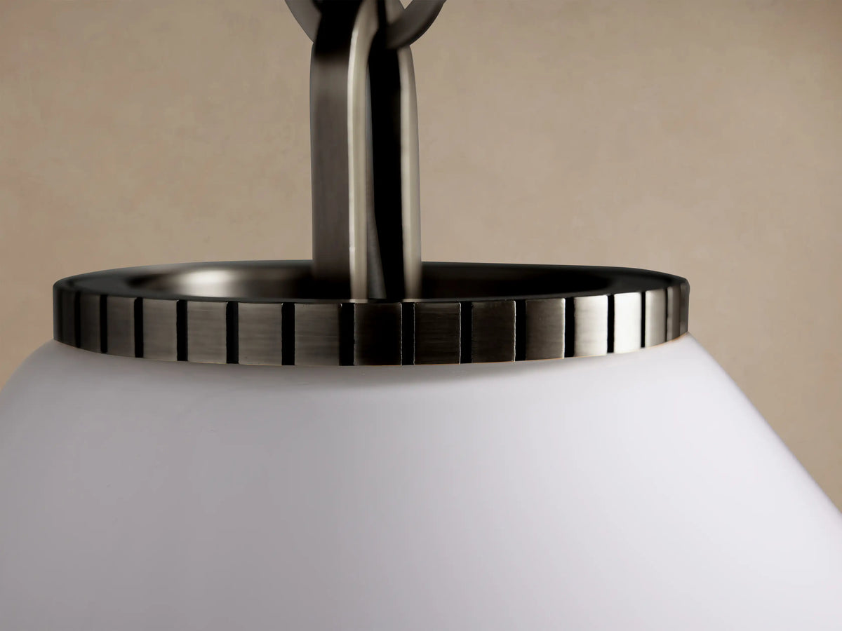 Wescott Cone Pendant with a white milk glass cone shade & dark bronze-finish fixture, suspended by a chain on a beige wall.