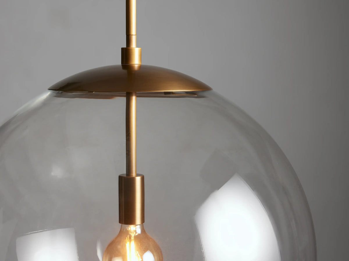 Wescott XL Globe Pendant with Rod in a brass finish featuring a clear glass globe. Visible is the E26 bulb inside.