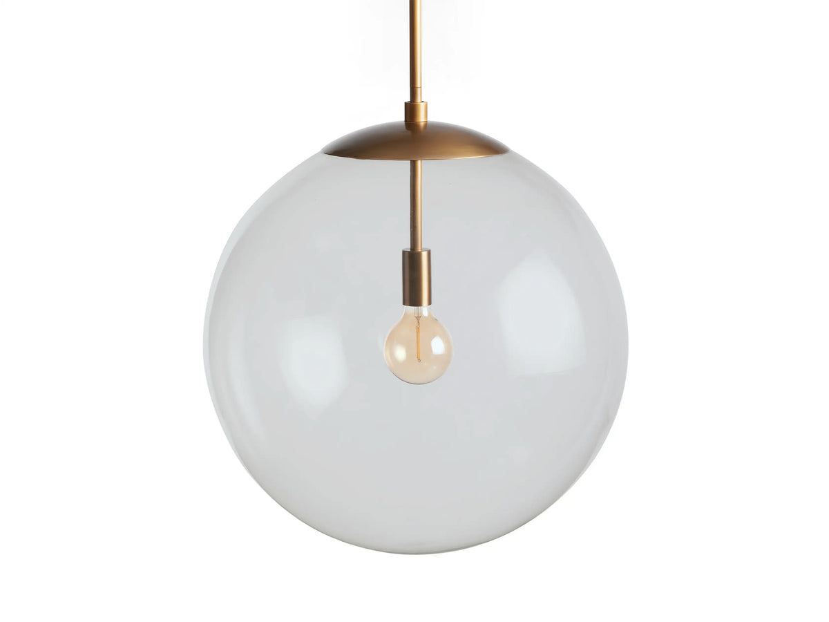 Clear globe pendant light with a slim brass rod and fixture. The transparent glass globe reveals a visible bulb inside.