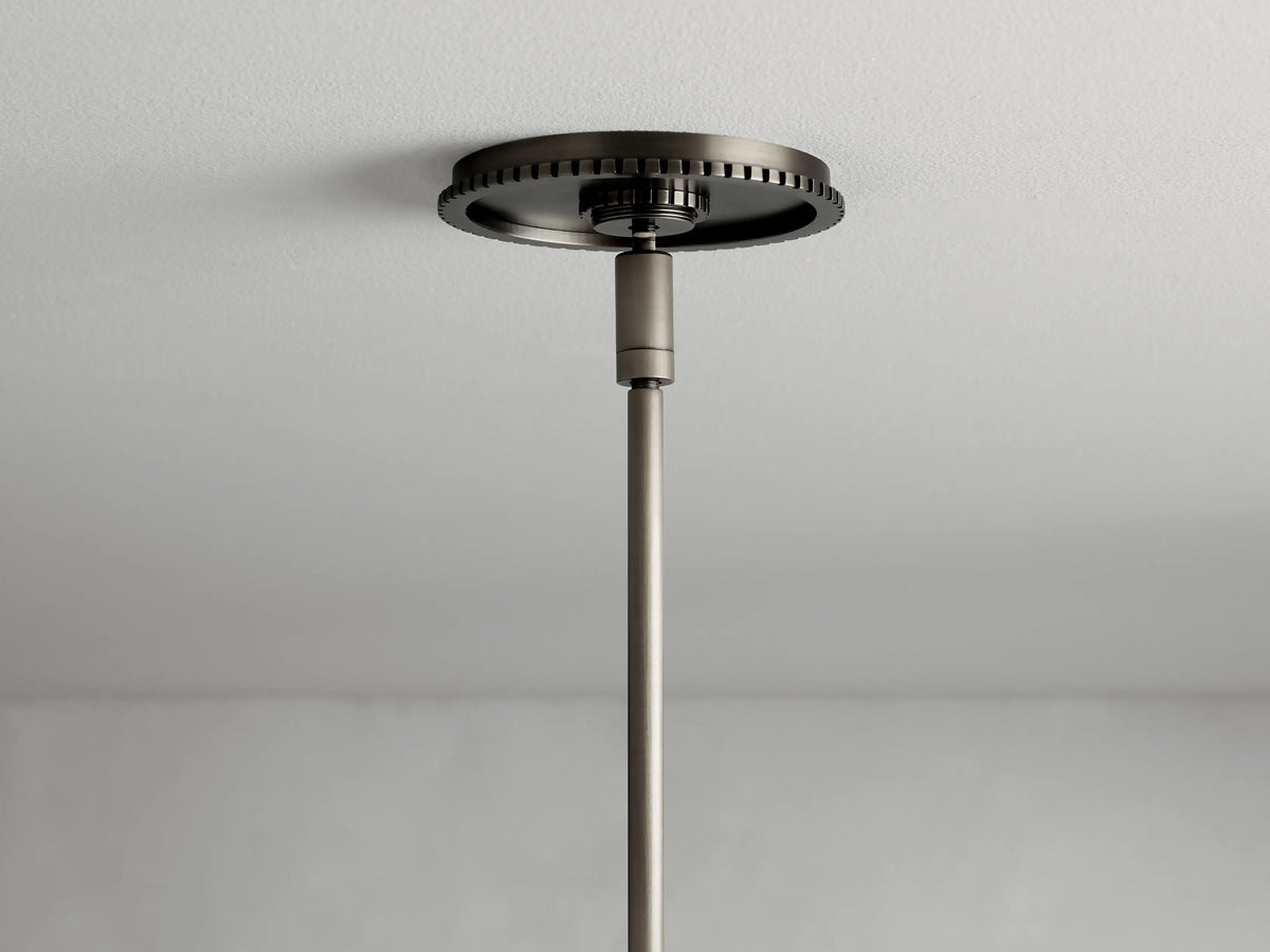 Close-up of Wescott XL Globe Pendant featuring textured metal ring in bronze finish, top of white glass globe visible, against gray background.