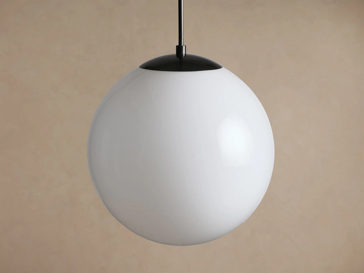 Wescott XL Globe Pendant with white milk glass globe and black rod, hanging centered against a neutral tan wall.