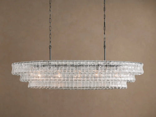 Ghiaccio Oval Chandelier: clear textured glass in tiered wavy segments, suspended by dark chains, with a soft inner glow.