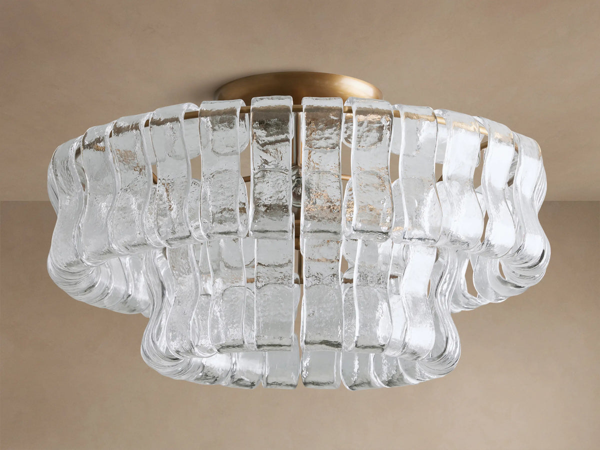 Ghiaccio Flush Mount: Brass base with clear, wavy textured glass strips in a layered, sculptural design, illuminated.