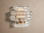 Ghiaccio Sconce: a layered wall light featuring clear, wavy textured glass and a warm, gold-toned frame, illuminated on a wall.