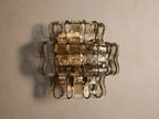 Ghiaccio Sconce: layered amber textured curved glass wall light emitting a warm glow on a neutral background.