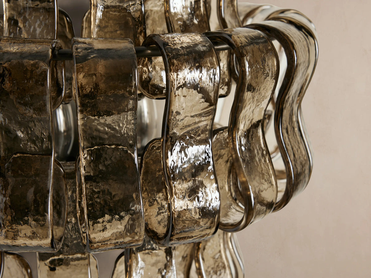 Ghiaccio Sconce: layered, wavy textured smoky-brown glass panels on a steel frame, mounted on a light beige wall.