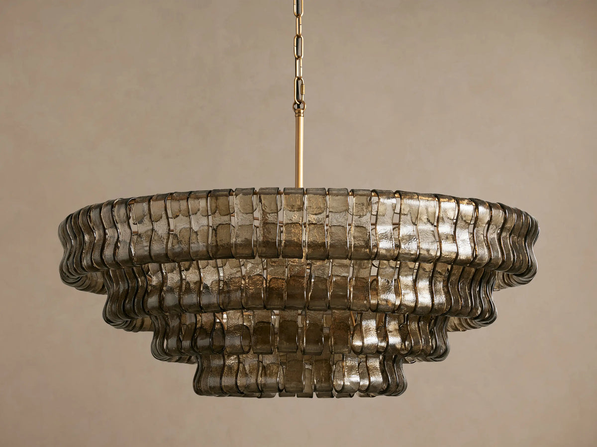 Ghiaccio Round Chandelier with three tiers of rippled, bronze-toned glass, hanging from a gold chain on a light background.