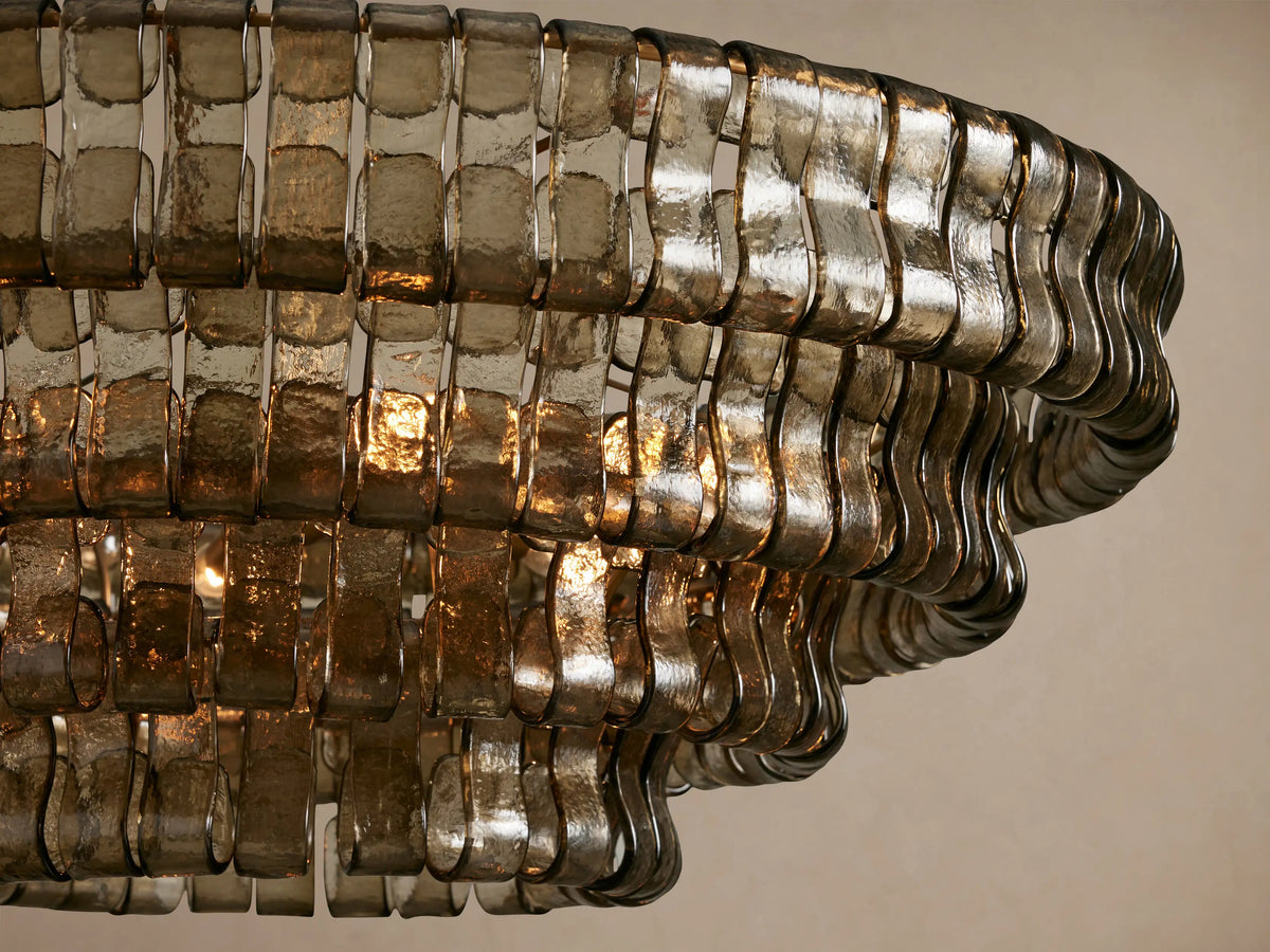 Close-up of Ghiaccio Round Chandelier with textured smoky gray curved glass strips, illuminated by warm internal lights.