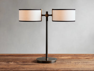 Daphne 2-Light Table Lamp with black-finished base and two white linen shades with black trim on a wooden surface.